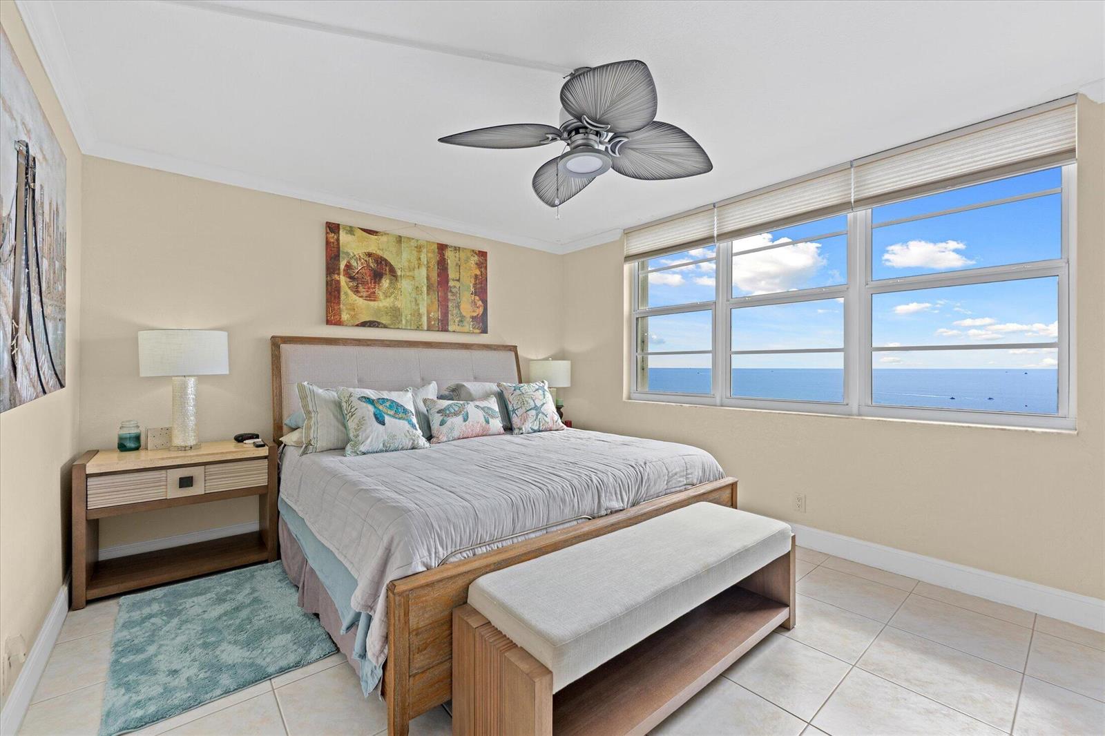 A bedroom features a king bed, a ceiling fan, and a large window overlooking the ocean — 750 N Ocean Boulevard # 710, Pompano Beach FL 33062, POMPANO BEACH, FL