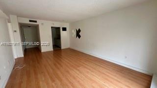 An empty room with light wood-look flooring and white walls leads to a doorway — 2350 NE 135th St # 212, North Miami FL 33181, NORTH MIAMI, FL