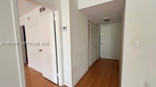 A hallway with light wood flooring, white walls, and several closed white doors — 2350 NE 135th St # 212, North Miami FL 33181, NORTH MIAMI, FL