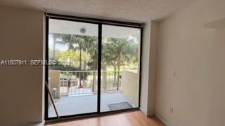 A room with light wood flooring features a large sliding glass door leading to a balcony — 2350 NE 135th St # 212, North Miami FL 33181, NORTH MIAMI, FL