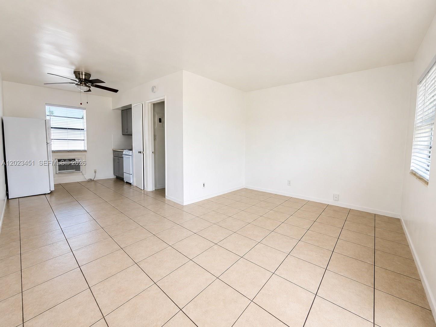 An open-concept living area features beige tile flooring, white walls, and a small kitchen nook — 1741-1743 Moffett St, Hollywood FL 33020, HOLLYWOOD, FL