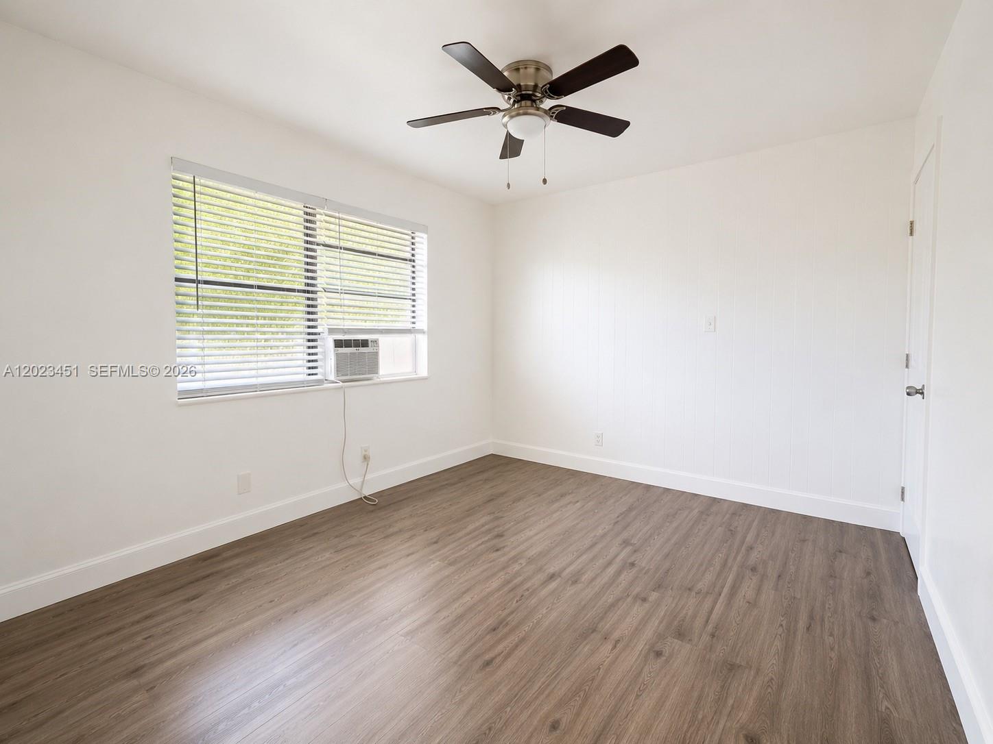 An empty bedroom features white walls, wood-look flooring, a ceiling fan, and a window unit — 1741-1743 Moffett St, Hollywood FL 33020, HOLLYWOOD, FL