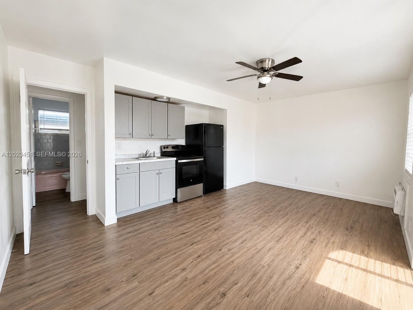 A studio apartment features a kitchenette with gray cabinets, black appliances, and wood-look flooring — 1741-1743 Moffett St, Hollywood FL 33020, HOLLYWOOD, FL