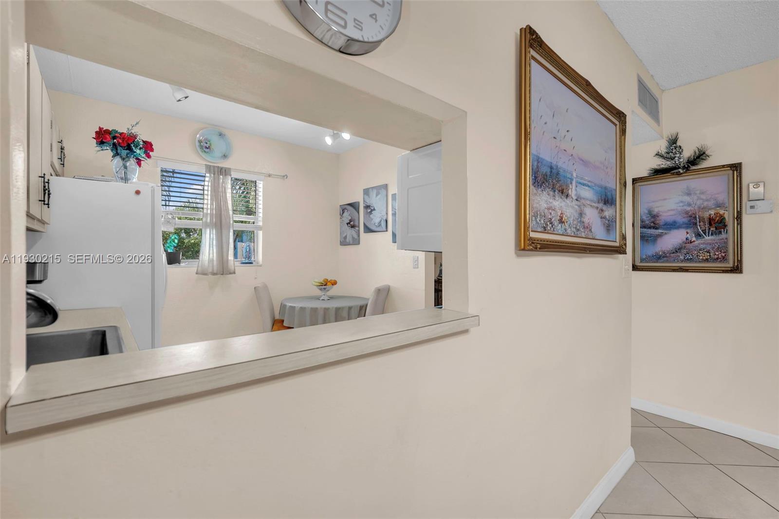 A kitchen with a pass-through window overlooks a small dining area with a round table — 3100 Holiday Springs Blvd # 304, Margate FL 33063, MARGATE, FL