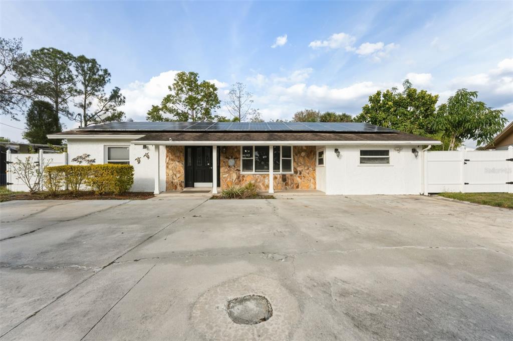 A single-story house with a stone facade, solar panels, and a large concrete driveway — 5017 STOLLS AVENUE, TAMPA, FL