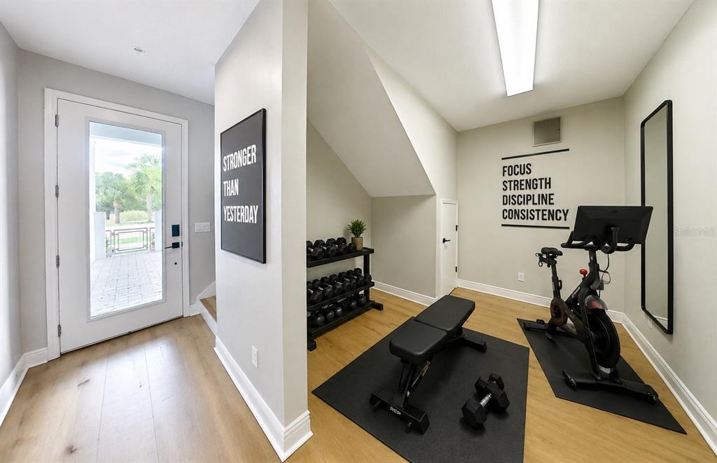 A home gym features a stationary bike, weight rack, bench, and motivational wall decals — 7227 NEMOURS PARKWAY, ORLANDO, FL