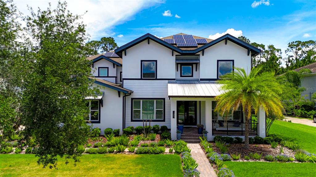 A two-story white house with dark trim, a metal roof, and solar panels — 12803 UPPER HARDEN AVENUE, ORLANDO, FL