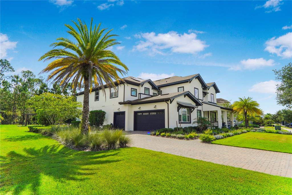 A two-story house with a paved driveway, dark garage doors, and a large palm tree — 12803 UPPER HARDEN AVENUE, ORLANDO, FL