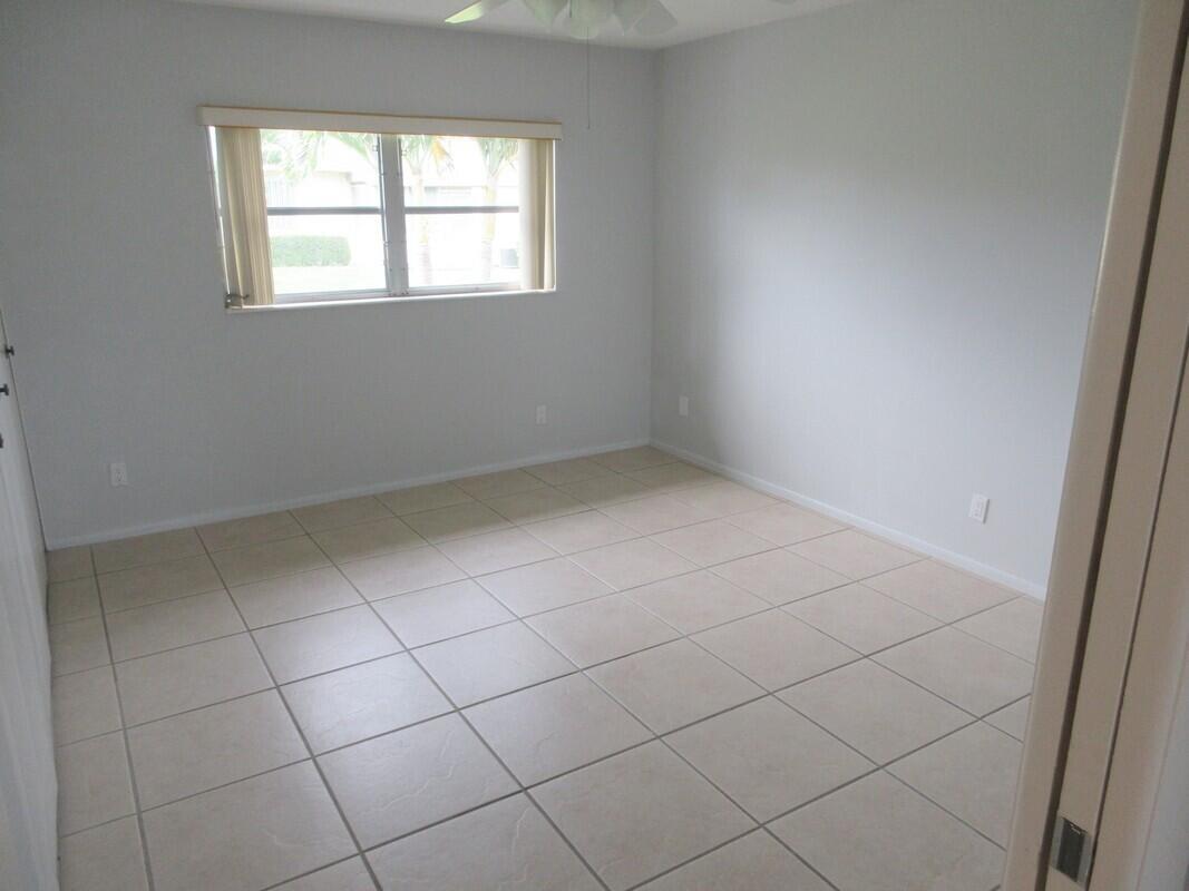 An empty bedroom features light gray walls, beige tile flooring, and a single window — 2572 Emory Drive E # J, West Palm Beach FL 33415, WEST PALM BEACH, FL