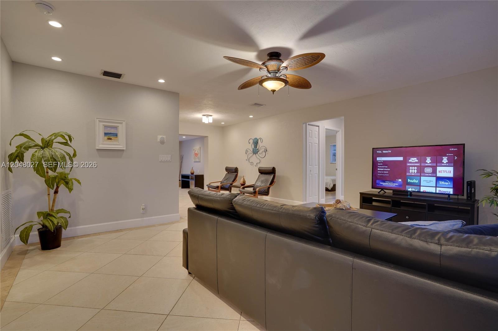 A living room features a dark leather sofa, a television, and a ceiling fan — 1660 NE 26th Ave # 0, Pompano Beach FL 33062, POMPANO BEACH, FL