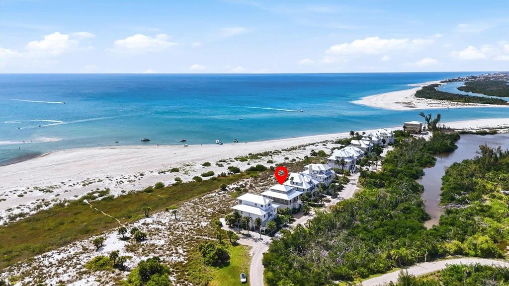 An aerial view shows a row of coastal houses situated between a beach and a lagoon — 6950 PALM ISLAND DRIVE, PLACIDA, FL