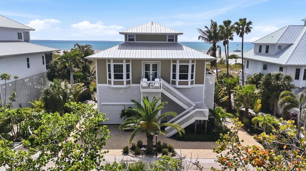 A three-story beach house with a metal roof, white siding, and an elevated wooden staircase — 6950 PALM ISLAND DRIVE, PLACIDA, FL