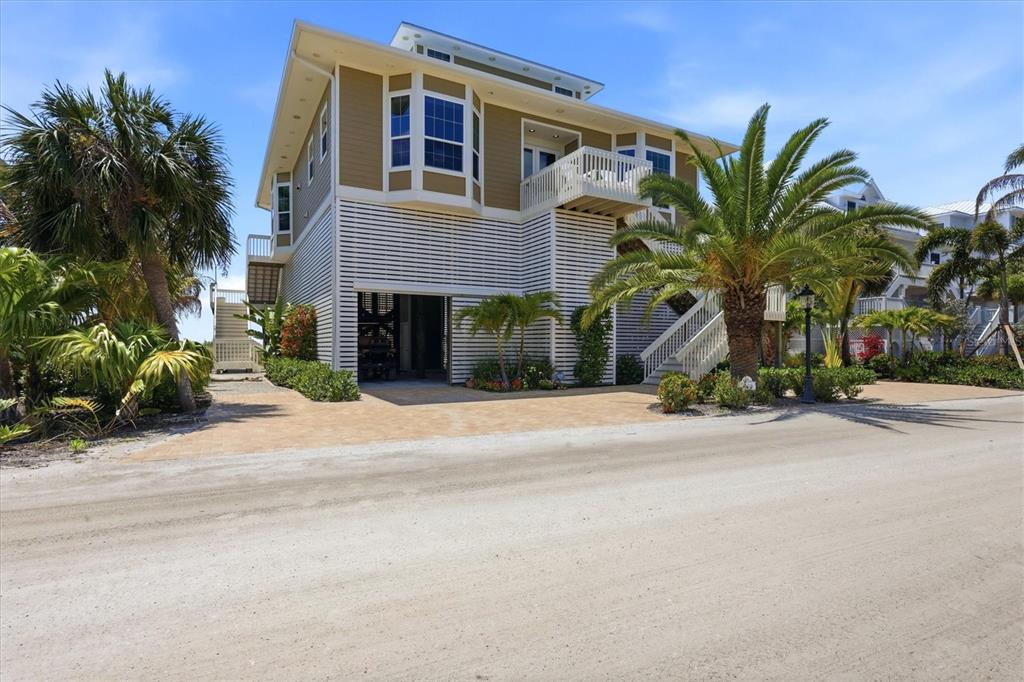 A multi-story house on stilts with a paved driveway and palm trees — 6950 PALM ISLAND DRIVE, PLACIDA, FL