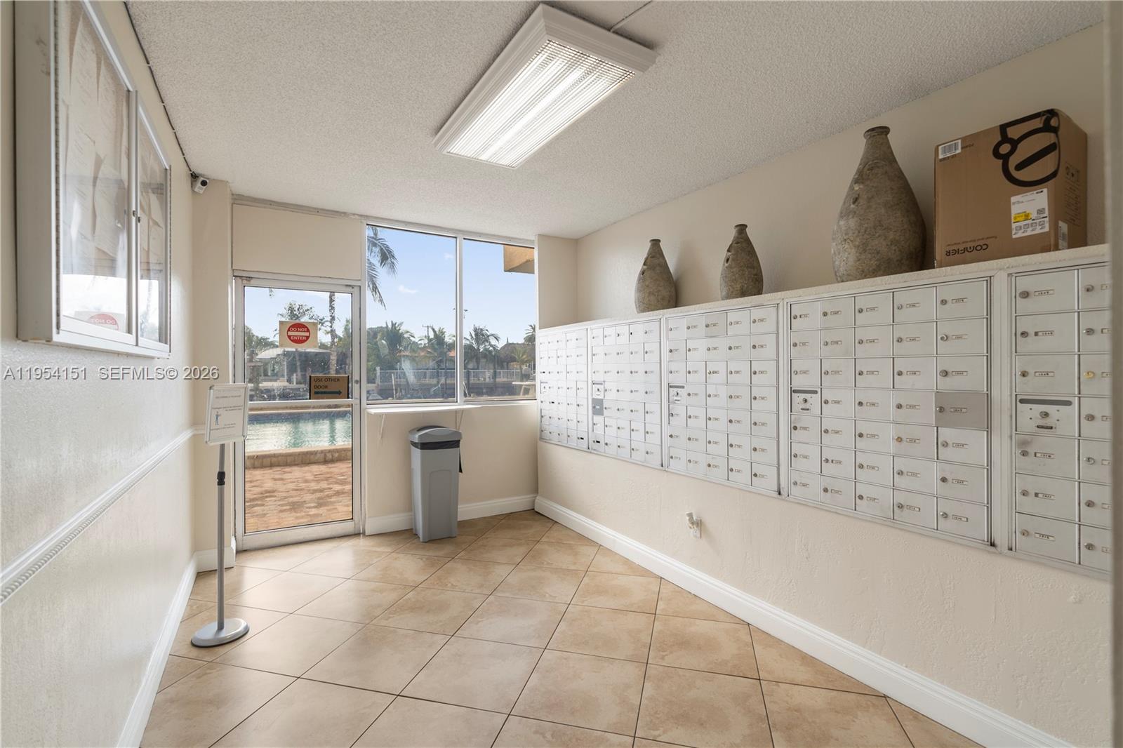 A mailroom features tiled floors, a glass door, and rows of metal mailboxes — 2350 NE 135th St # 1202, North Miami FL 33181, NORTH MIAMI, FL