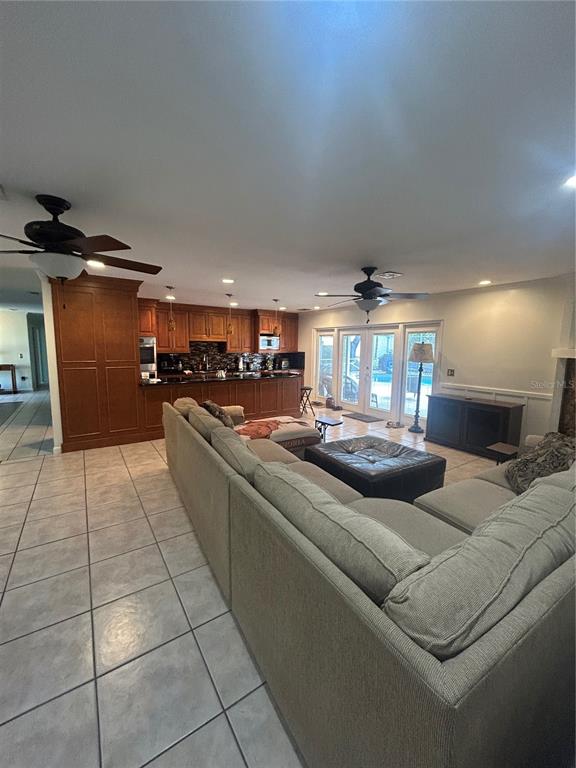 A living room with a large sectional sofa faces an open kitchen with wooden cabinetry — 2935 PLANTATION ROAD, WINTER HAVEN, FL