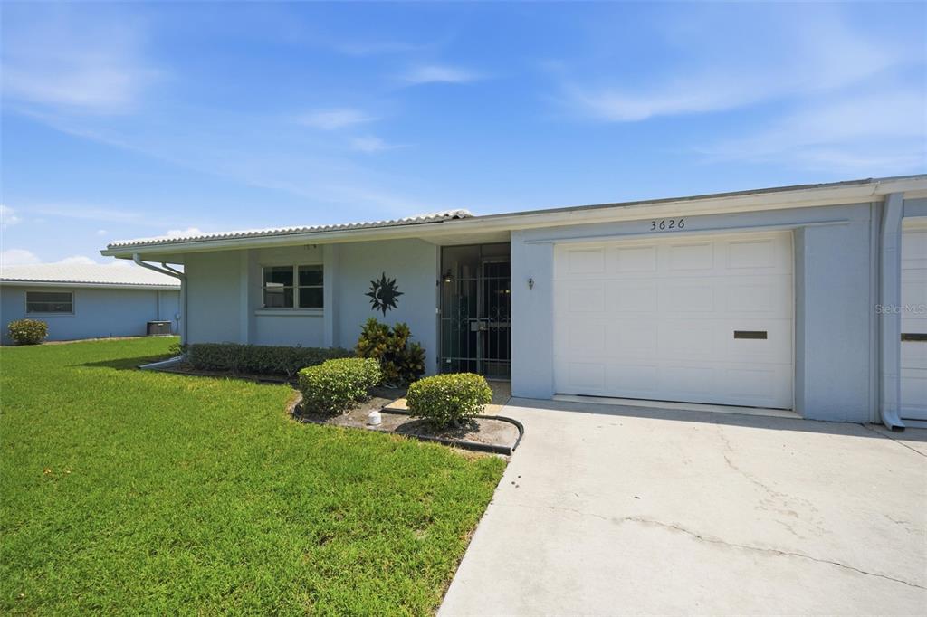 A single-story house with a white garage door, light blue siding, and a front lawn — 3626 MEDFORD LANE UNIT 1537, SARASOTA, FL