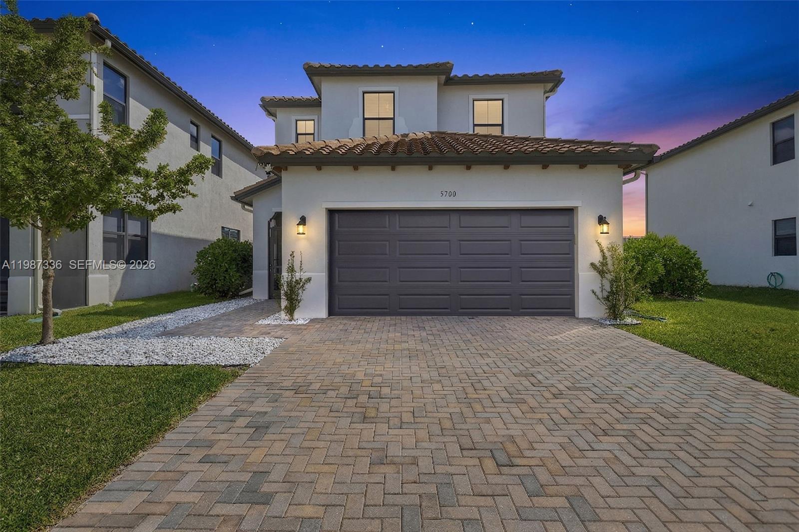 A two-story house with a paved driveway, a dark garage door, and a tiled roof — 5700 Argento, Ave Maria FL 34142, AVE MARIA, FL