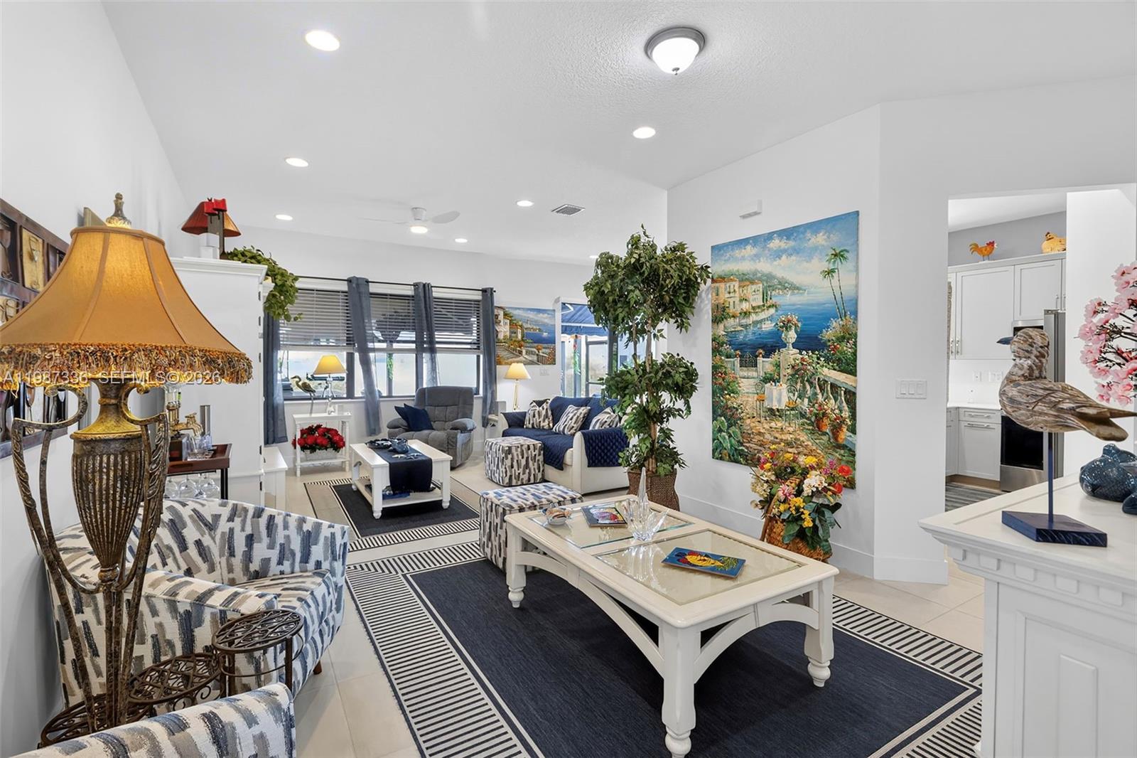 A living room features blue and white patterned furniture, a large coastal painting, and rugs — 5700 Argento, Ave Maria FL 34142, AVE MARIA, FL