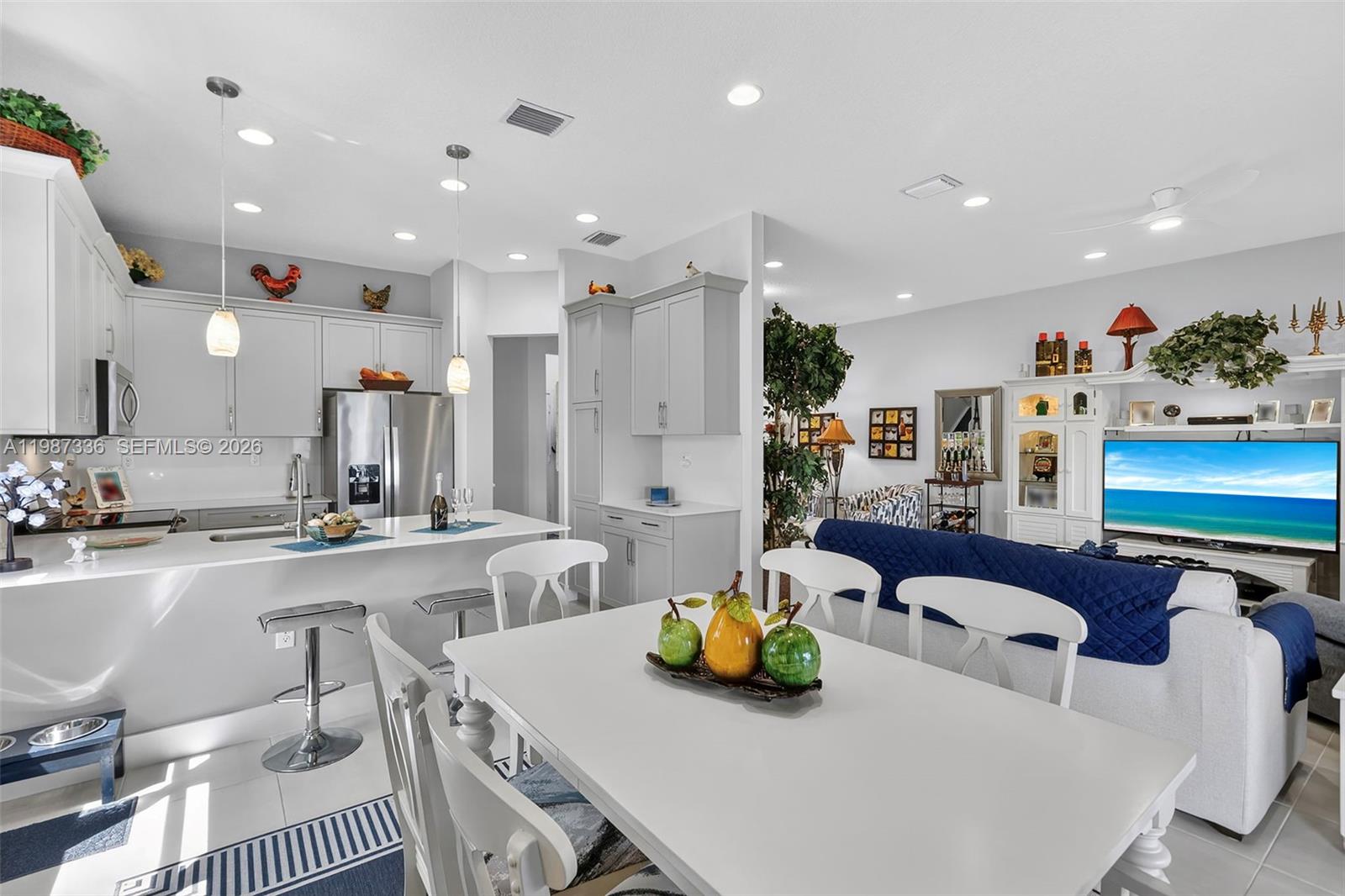 An open-concept kitchen and dining area features white cabinetry, a breakfast bar, and living space — 5700 Argento, Ave Maria FL 34142, AVE MARIA, FL