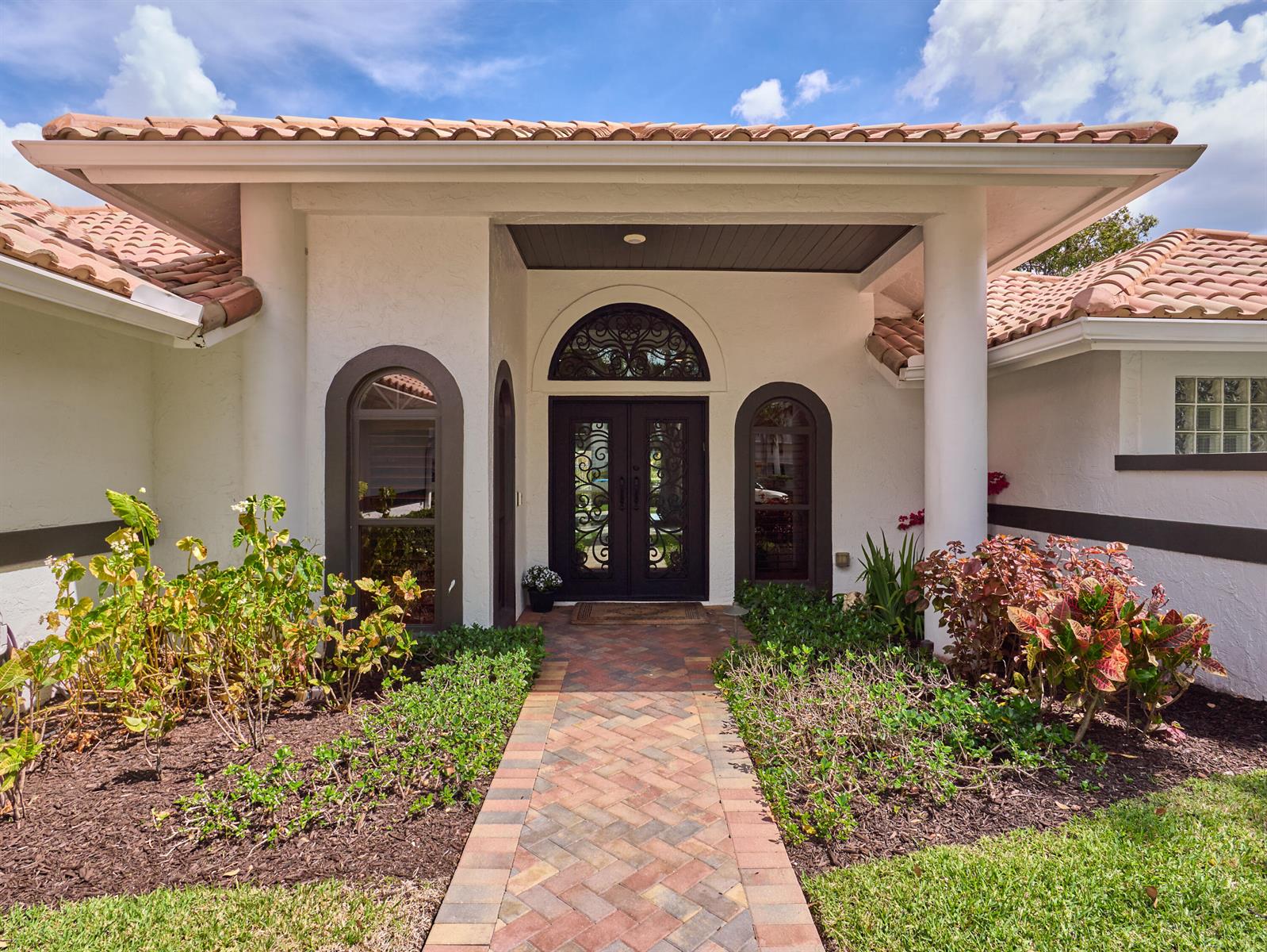 The exterior of a house features a brick walkway leading to a double front door — 3700 Embassy Drive, West Palm Beach FL 33401, WEST PALM BEACH, FL