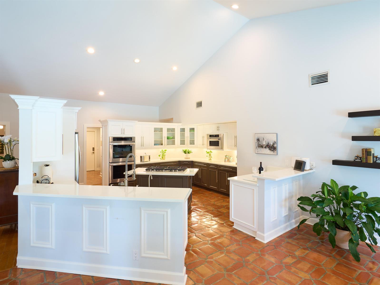 A kitchen with white and dark cabinets, a center island, and terracotta tile flooring — 3700 Embassy Drive, West Palm Beach FL 33401, WEST PALM BEACH, FL
