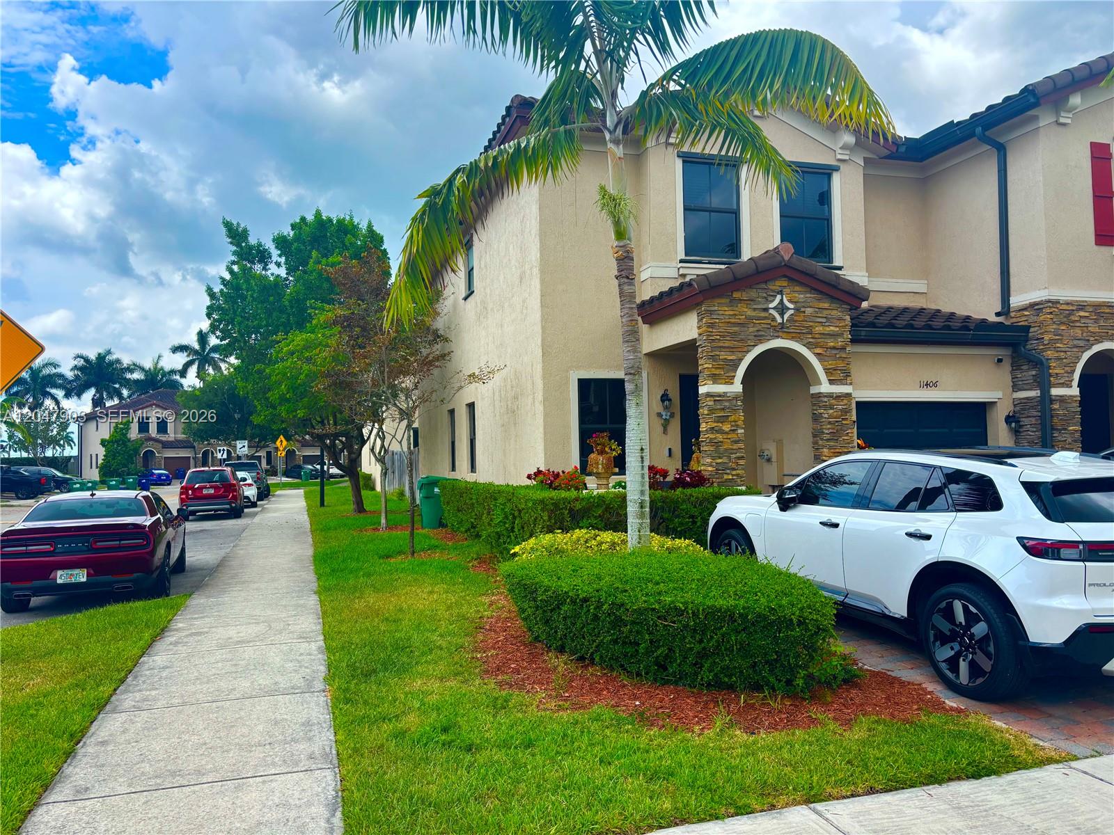 A two-story suburban house features a stone-accented facade, a palm tree, and a paved driveway — 11406 SW 252nd Ter, Homestead FL 33032, HOMESTEAD, FL