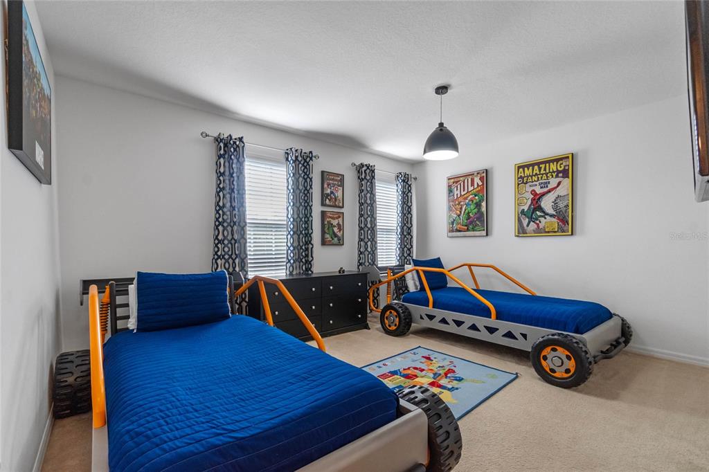 A bedroom features two race car-themed beds, comic book wall art, and a patterned area rug — 2652 SANTOSH COVE, KISSIMMEE, FL