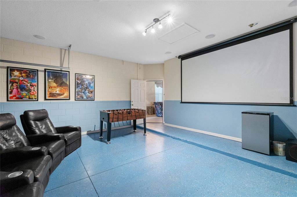 A basement media room features a projector screen, foosball table, leather recliners, and blue flooring — 2652 SANTOSH COVE, KISSIMMEE, FL