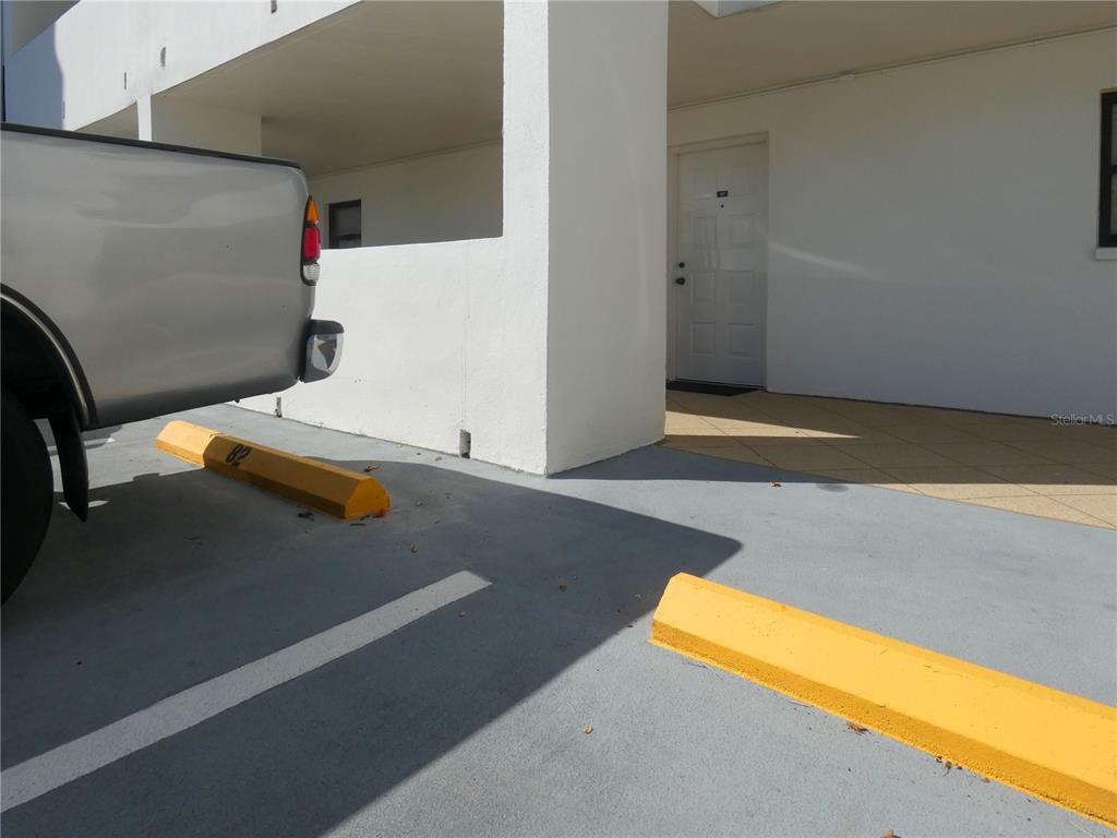 A silver pickup truck is parked in a space next to a white building entrance — 1230 GULF BOULEVARD UNIT 207, CLEARWATER BEACH, FL