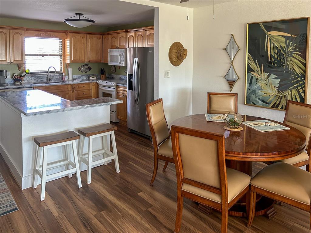 A kitchen with wood cabinets and a marble-topped island next to a dining area — 1230 GULF BOULEVARD UNIT 207, CLEARWATER BEACH, FL