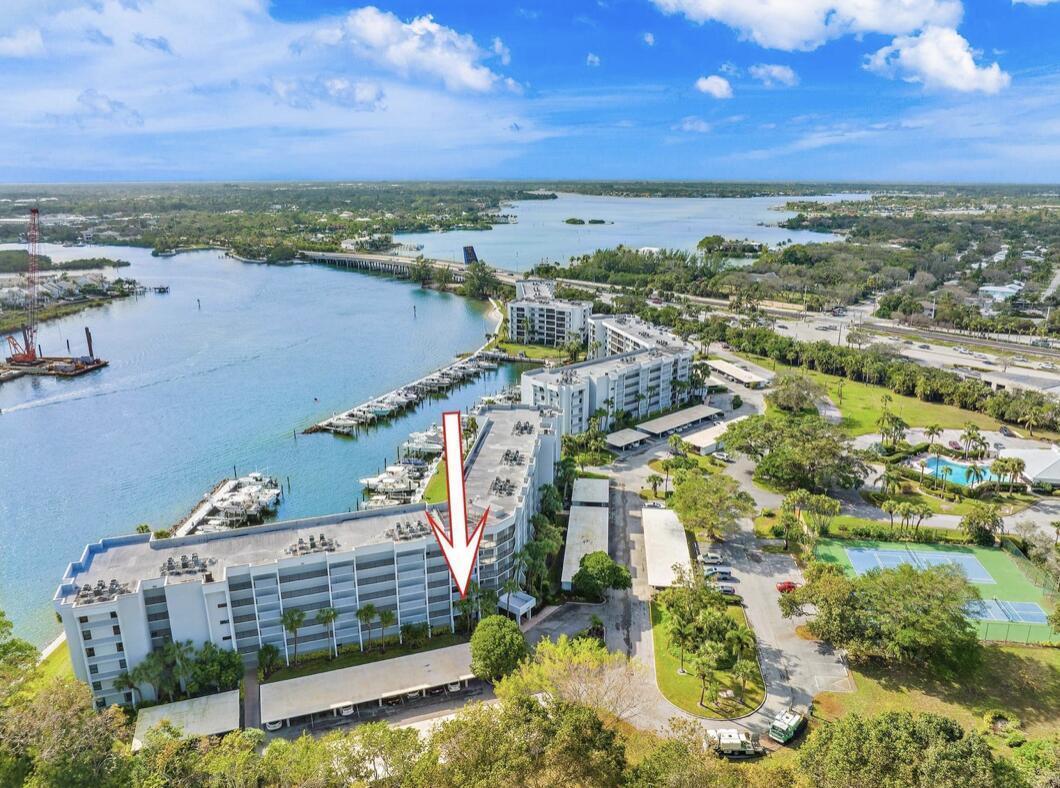 An aerial view shows a multi-story waterfront condominium building with a marina and tennis courts — 1748 Jupiter Cove Drive # A, Jupiter FL 33469, JUPITER, FL