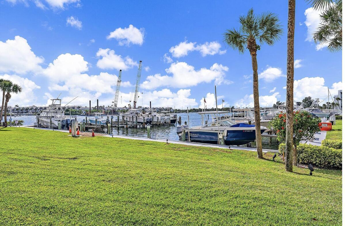 A grassy lawn overlooks a marina with several docked boats under a blue sky — 1748 Jupiter Cove Drive # A, Jupiter FL 33469, JUPITER, FL