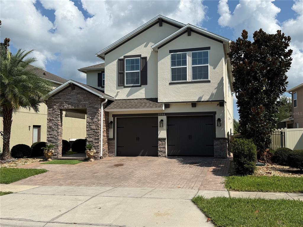 A two-story house with a stone-accented entryway, two garage doors, and a paved driveway — 2706 MONTICELLO WAY, KISSIMMEE, FL