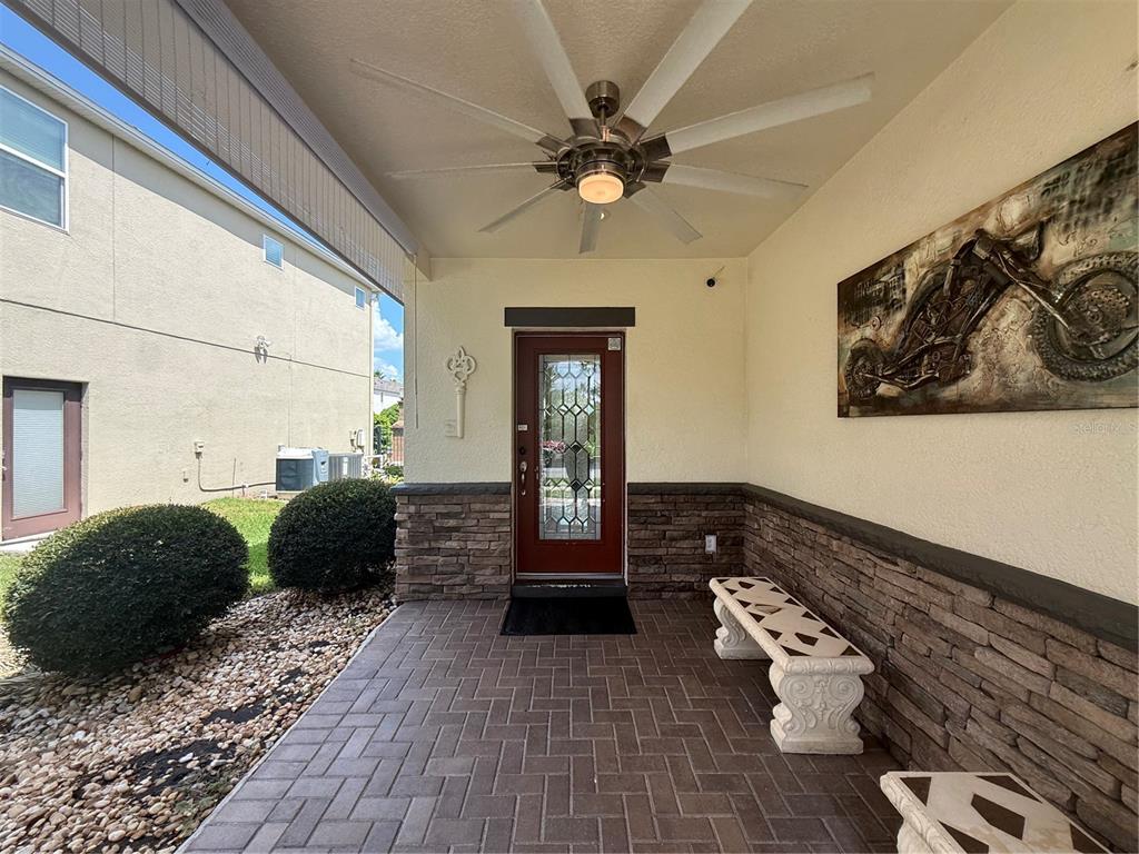 A covered patio features a brick paver floor, stone siding, a ceiling fan, and a bench — 2706 MONTICELLO WAY, KISSIMMEE, FL