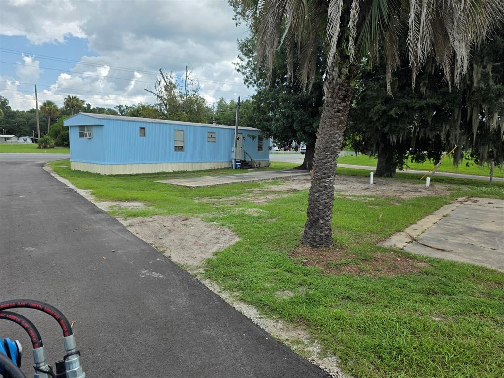 A blue mobile home sits on a grassy lot next to a paved driveway — 10446 COUNTY ROAD 44, LEESBURG, FL