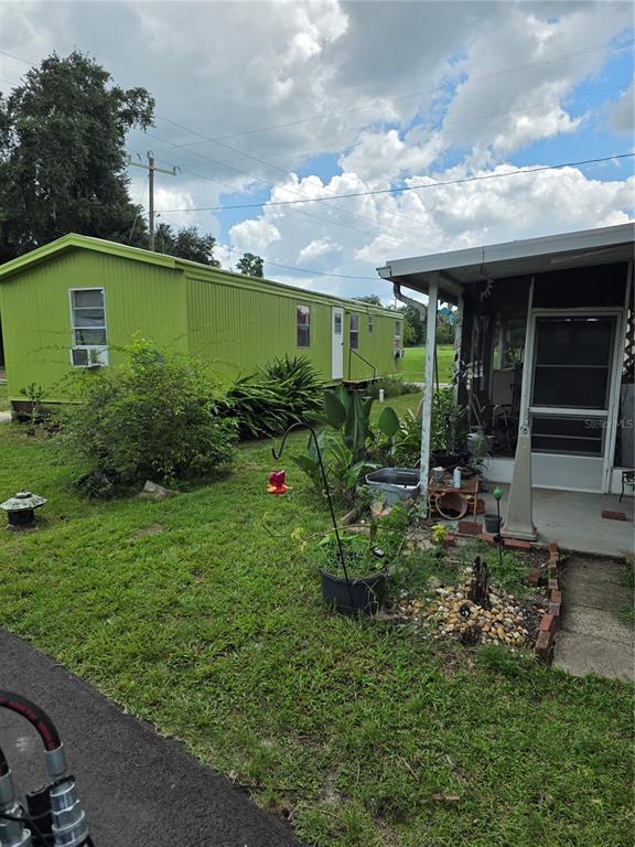A lime green mobile home sits on a grassy lot next to a screened porch — 10446 COUNTY ROAD 44, LEESBURG, FL