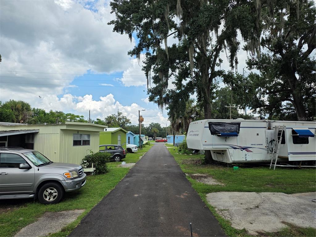 A paved road runs between mobile homes and parked vehicles under large, moss-covered trees — 10446 COUNTY ROAD 44, LEESBURG, FL
