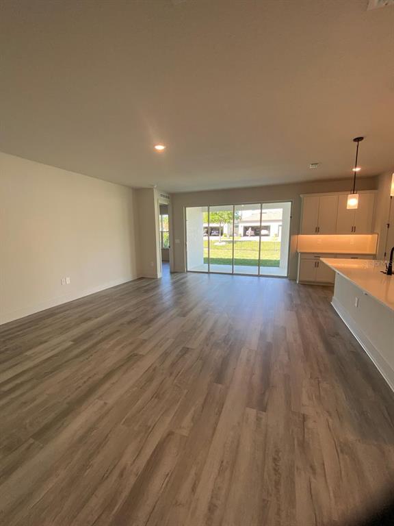 A modern kitchen features white cabinetry, a large central island with bar seating, and stainless appliances — 9493 EMERALD BERRY DRIVE, WINTER GARDEN, FL