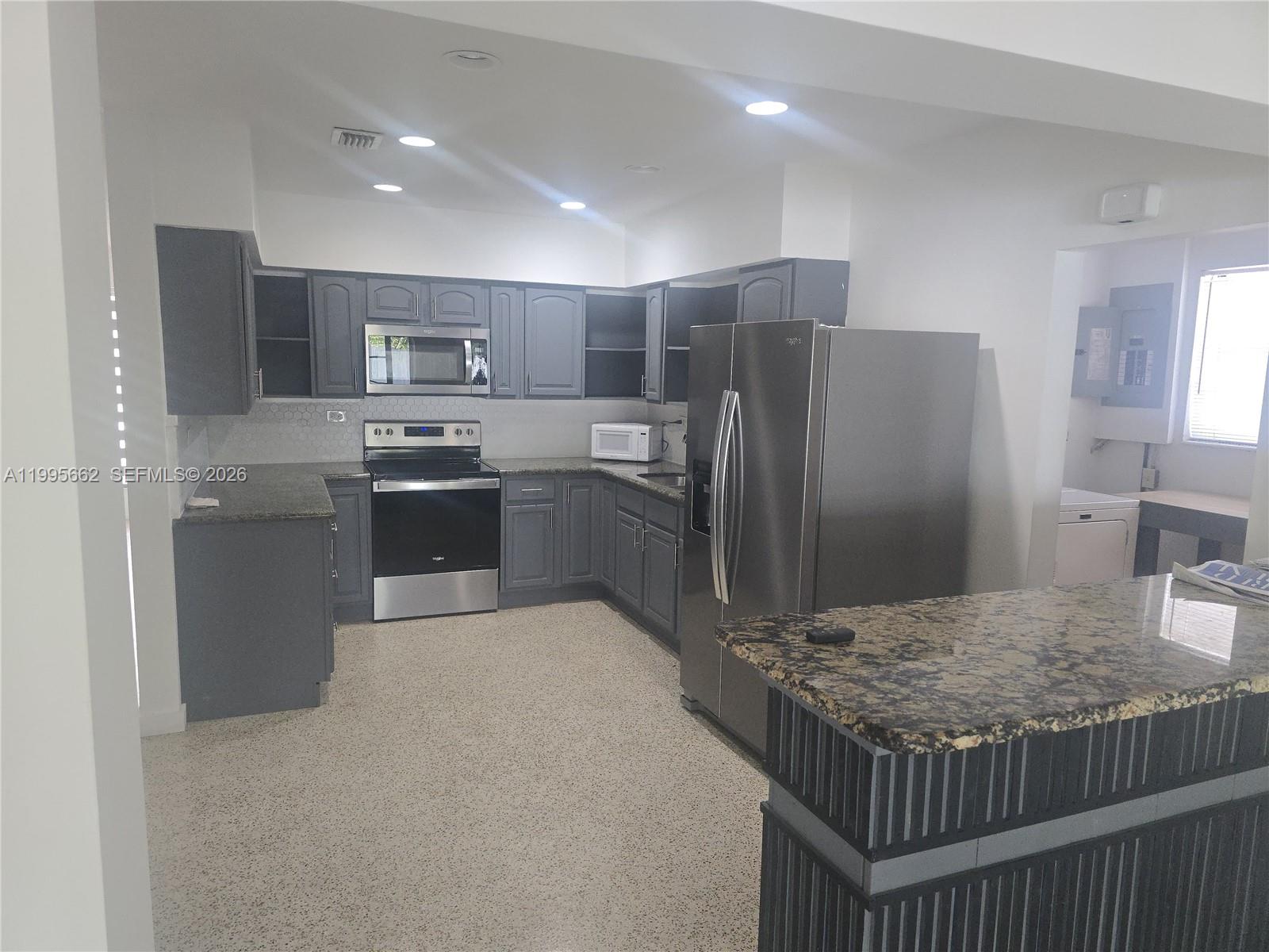 A kitchen features gray cabinets, stainless steel appliances, granite countertops, and a speckled floor — 9725 SW 15th St, Miami FL 33174, MIAMI, FL