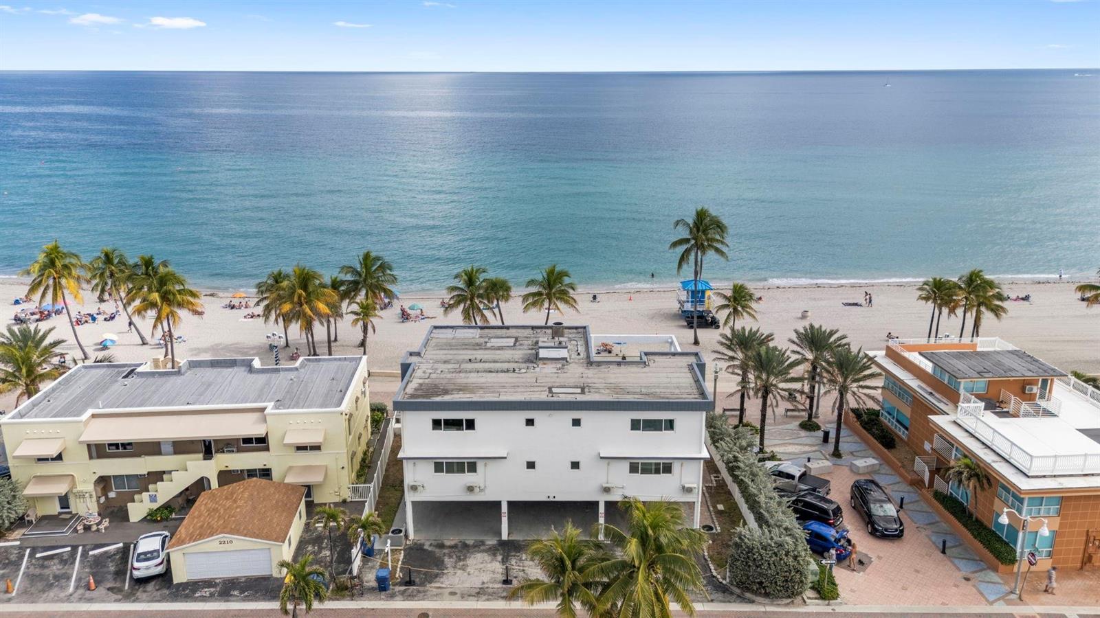 An aerial view shows a white multi-story building situated directly on a sandy beach — 2201 N Surf Road, Hollywood FL 33019, HOLLYWOOD, FL
