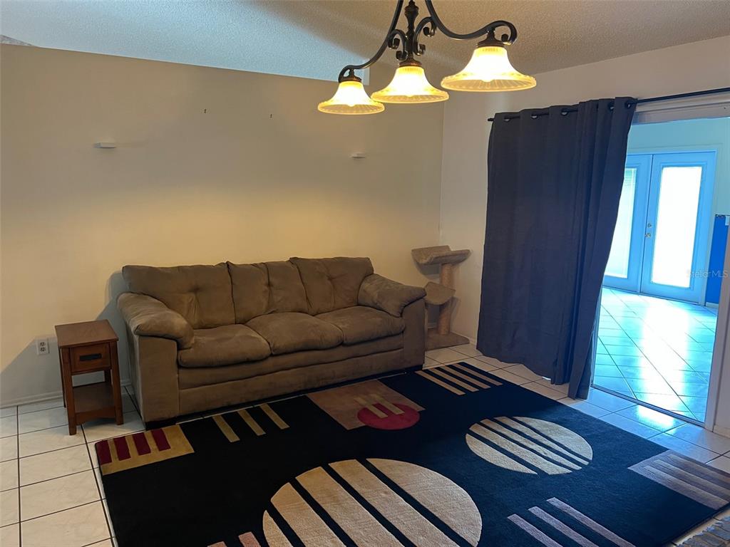 A living room features a brown sofa, a patterned area rug, and a hanging light fixture — 330 BONNIE LANE, ORANGE CITY, FL