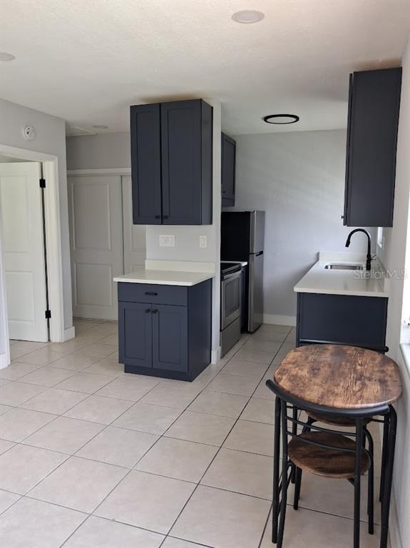 A kitchen features dark blue cabinets, white countertops, stainless steel appliances, and a small dining table — 217 BANANA STREET, TARPON SPRINGS, FL