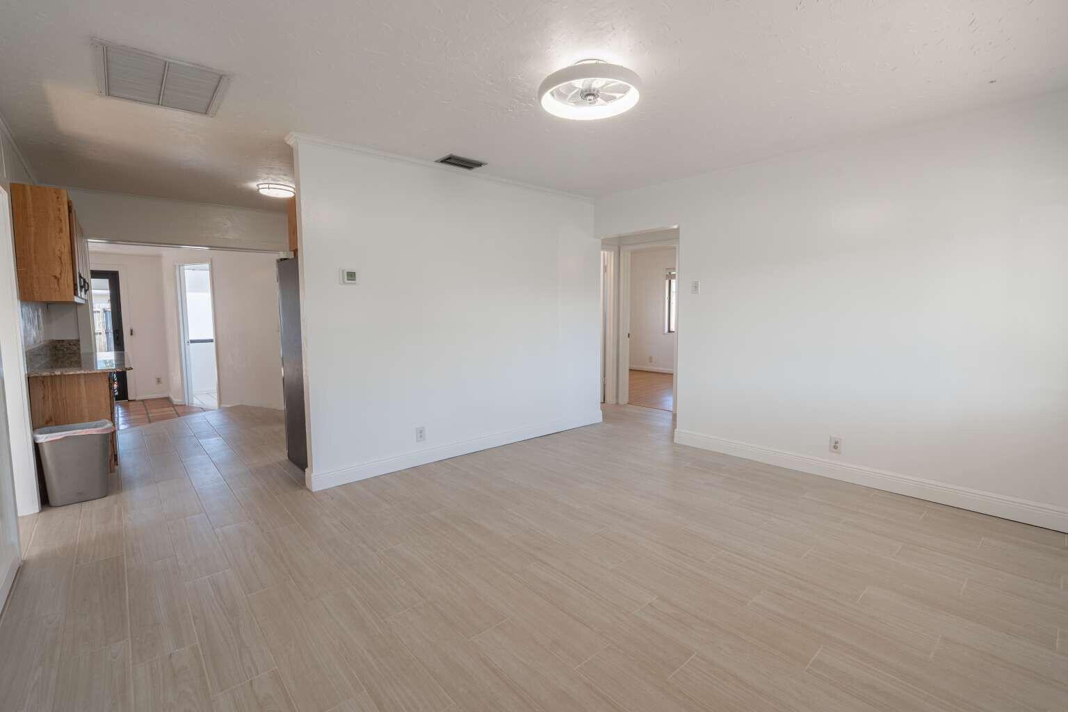 An empty living room with light wood-look tile flooring, white walls, and a ceiling light — 3110 Scanlan Avenue, Lake Worth FL 33461, LAKE WORTH, FL