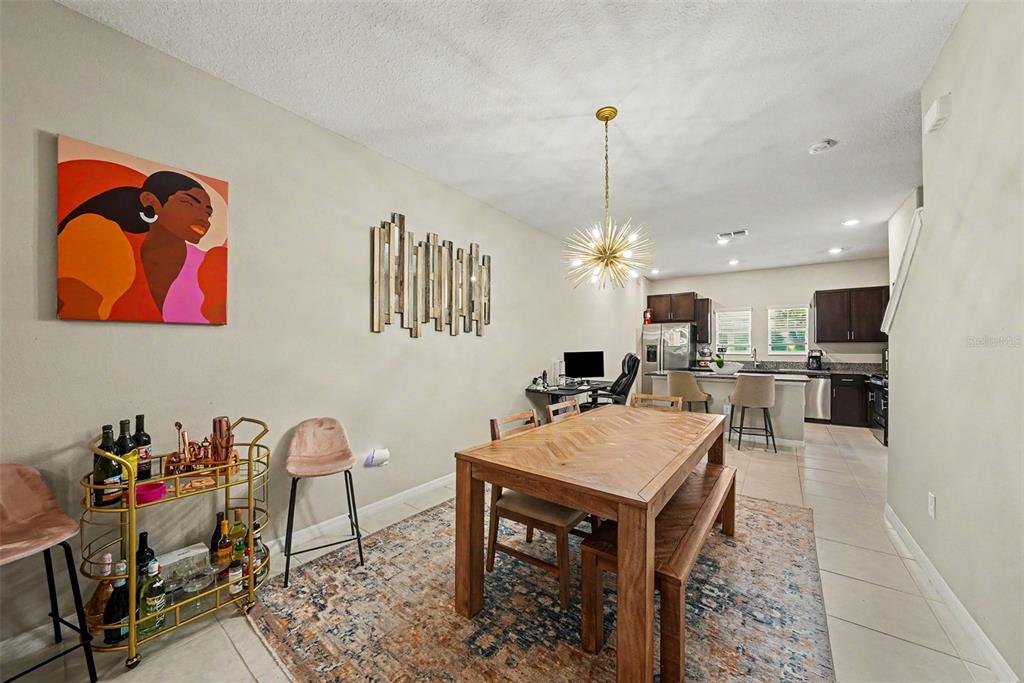A dining area with a wooden table, bar cart, and open kitchen in the background — 4524 TUSCAN LOON DRIVE, TAMPA, FL
