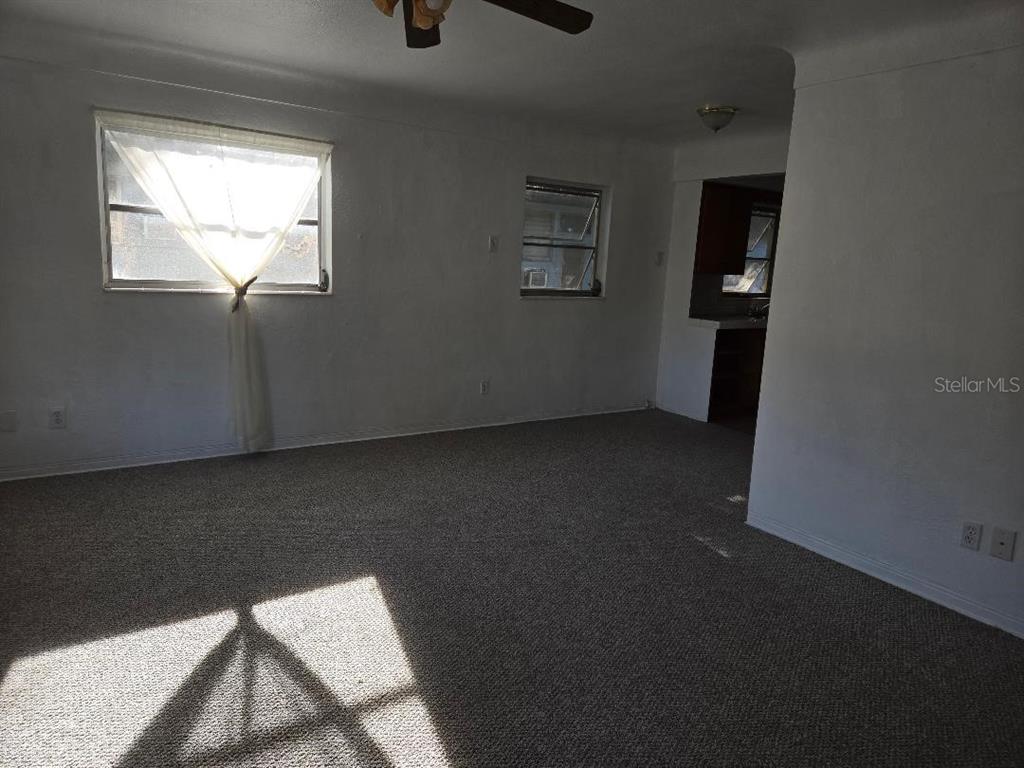 A living room with beige carpet, white walls, two windows, and a ceiling fan — 5715 21ST AVENUE S, GULFPORT, FL