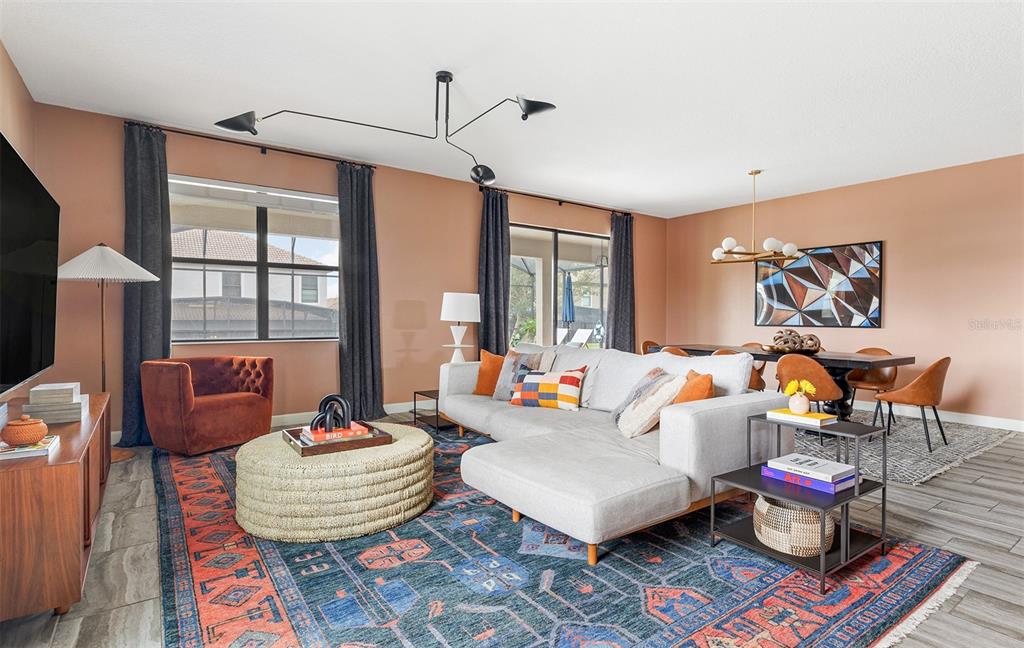 A living room features a grey sectional sofa, a round ottoman, and a patterned rug — 1518 ROLLING FAIRWAY DRIVE, DAVENPORT, FL