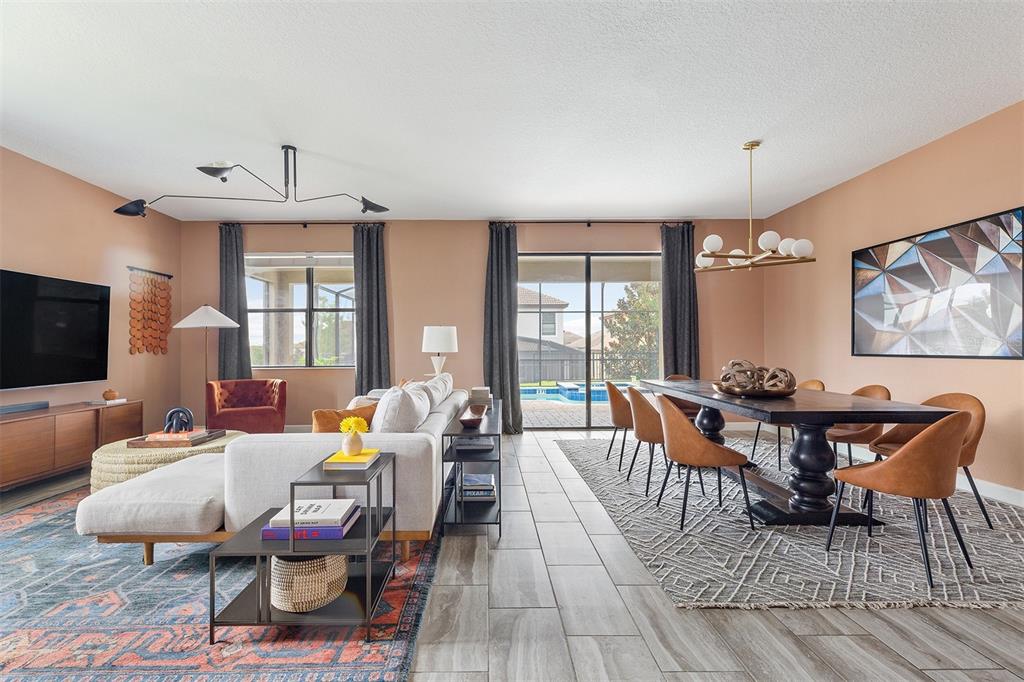 An open-concept living and dining room with tile floors, a pool view, and modern decor — 1518 ROLLING FAIRWAY DRIVE, DAVENPORT, FL