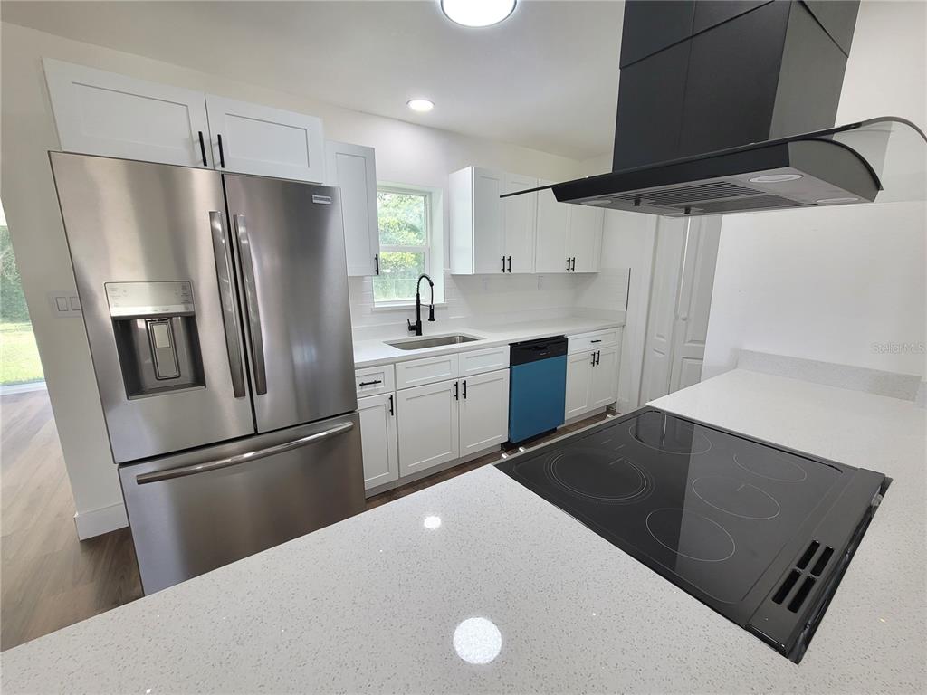 A kitchen features white cabinets, stainless steel appliances, a black range hood, and a ceiling fan — 8 FLAMEVINE LANE, DEBARY, FL