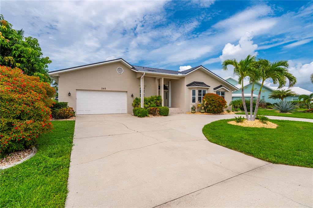 A single-story house with a white garage door, a concrete driveway, and palm trees — 265 BELVEDERE COURT, PUNTA GORDA, FL