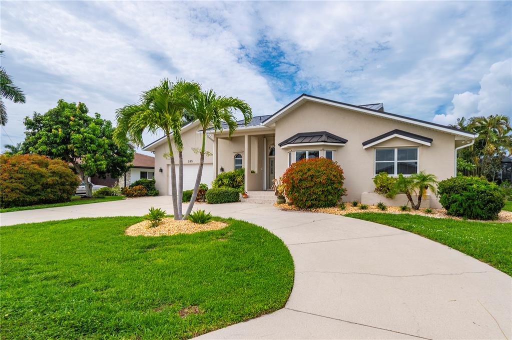A single-story house with a beige exterior, a curved driveway, and palm trees in the yard — 265 BELVEDERE COURT, PUNTA GORDA, FL